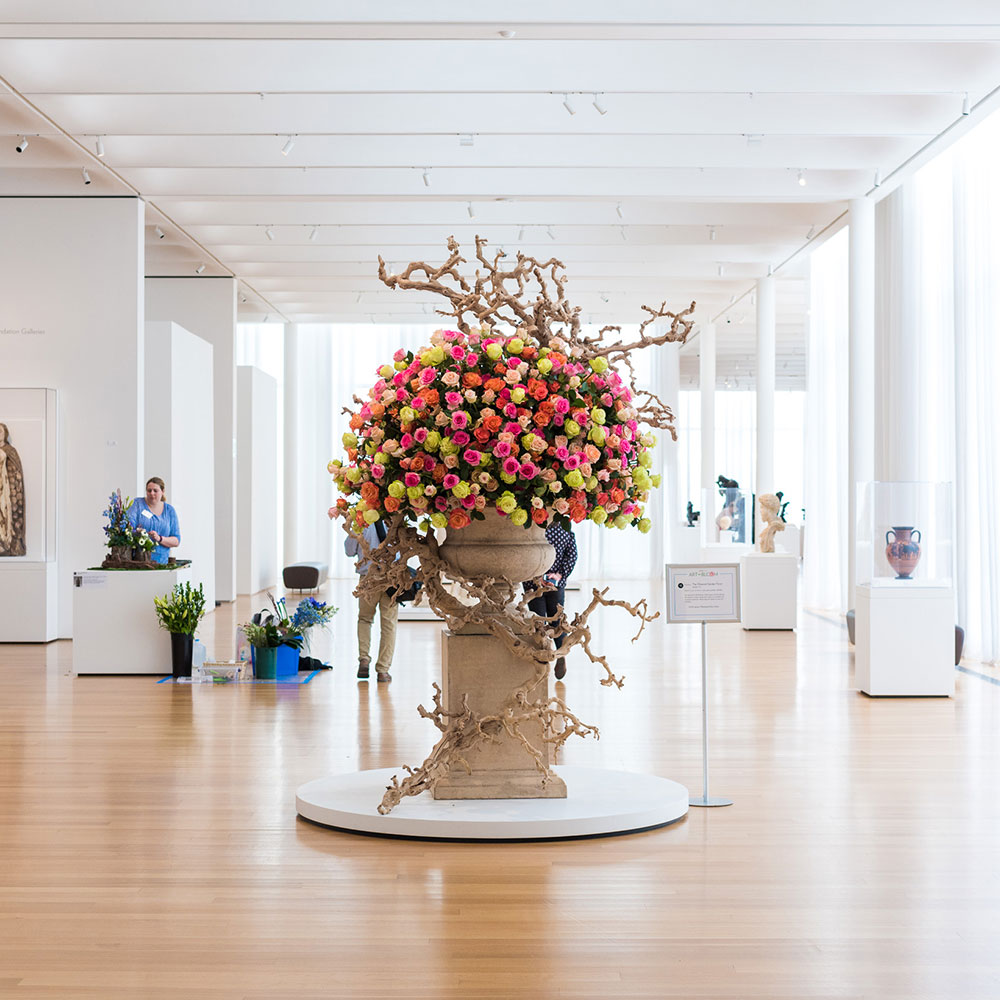 A large stone vase holding pink, red, and yellow flowers in the center of a lobby at the North Carolina Museum of Art in Wake County