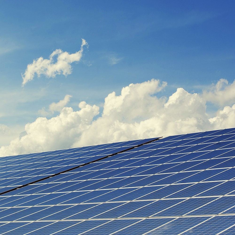 Solar panels reflect the sunlight with clouds in the background