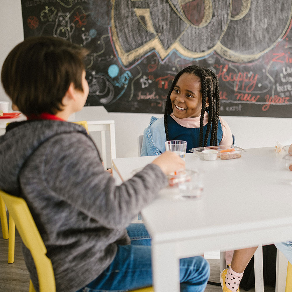 Young children sit at a desk in a classroom