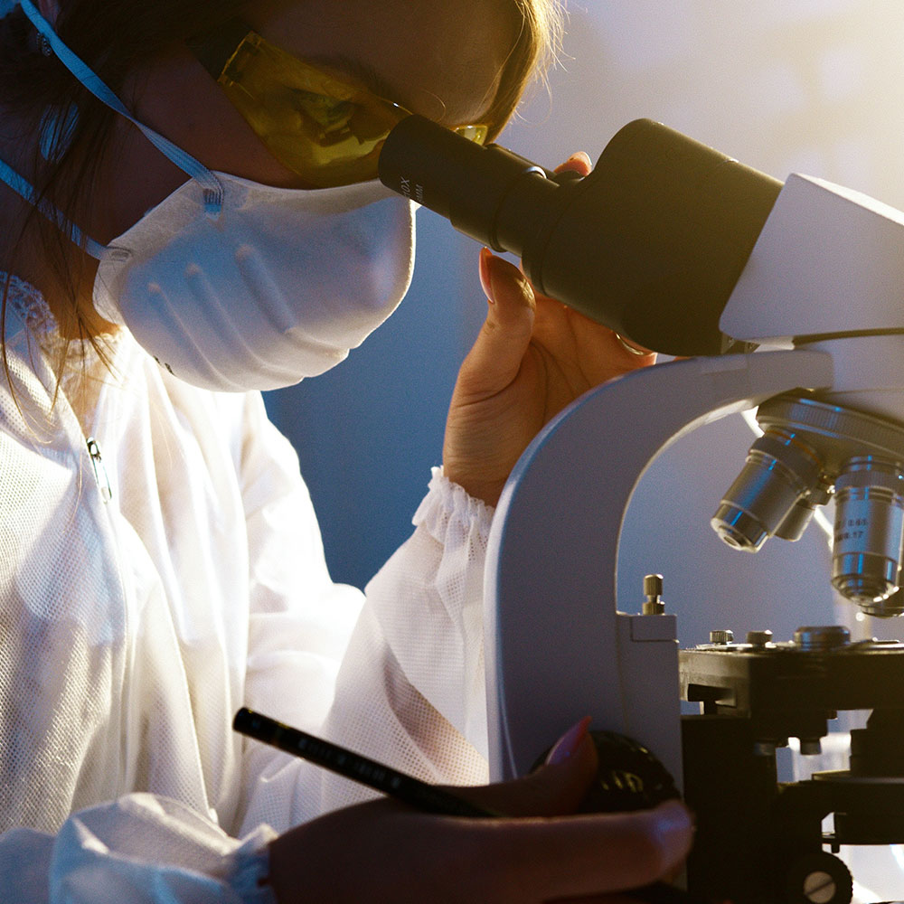 A woman looking into an advanced microscope in a research lab in Wake County