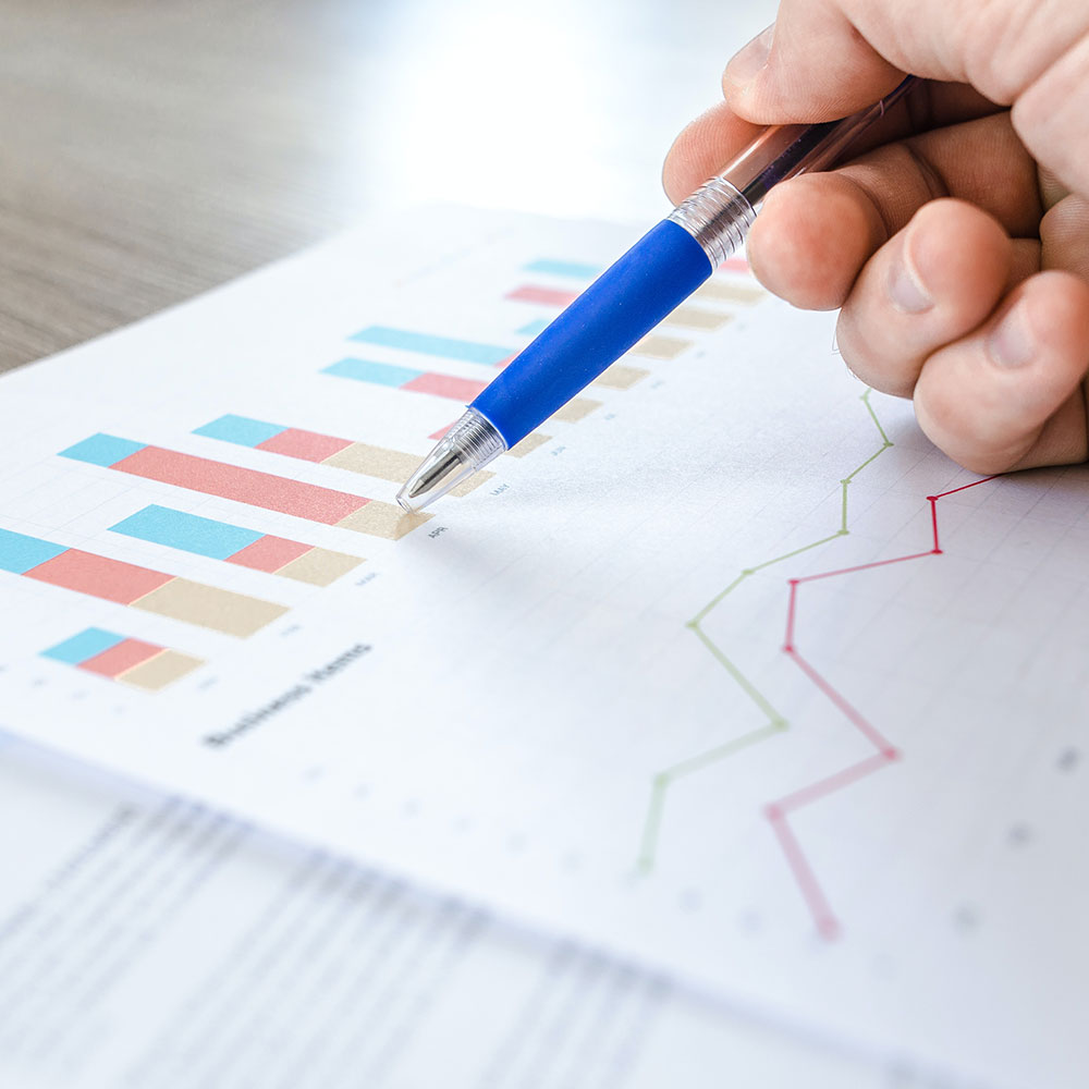 A person holds a pen to a piece of paper with a graph on it