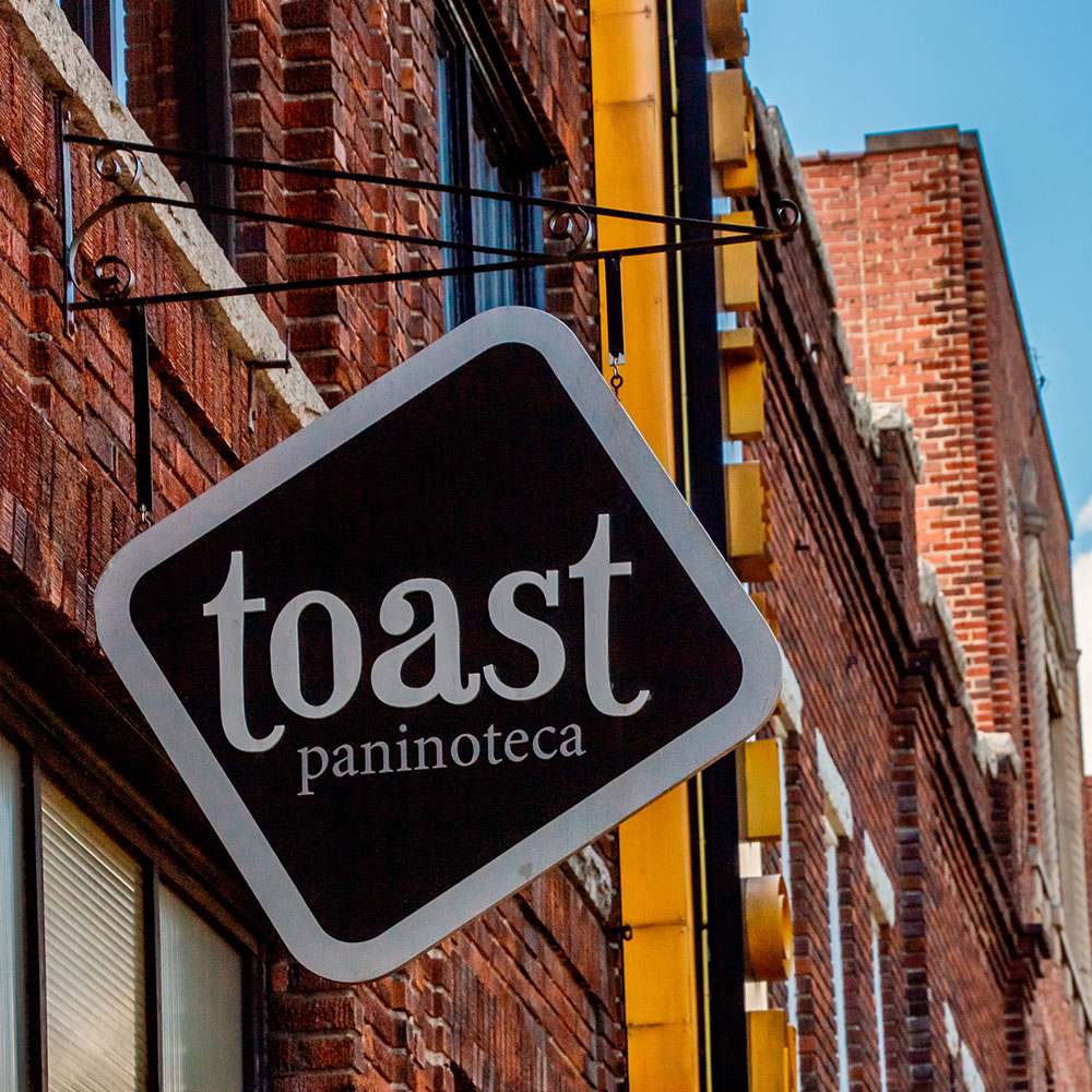 A diamond black sign that says Toast Paninoteca in Durham in Wake County