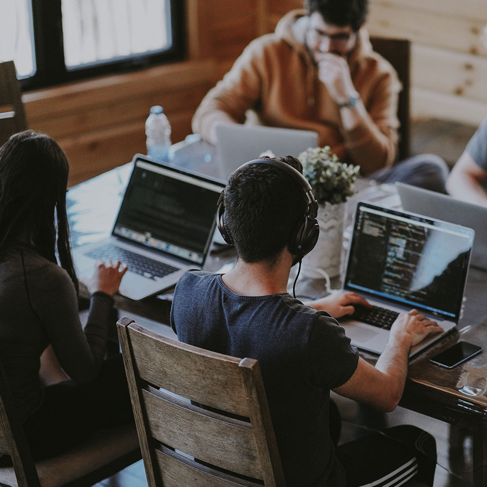 A group of coworkers meet in a conference room at a desk for a meeting