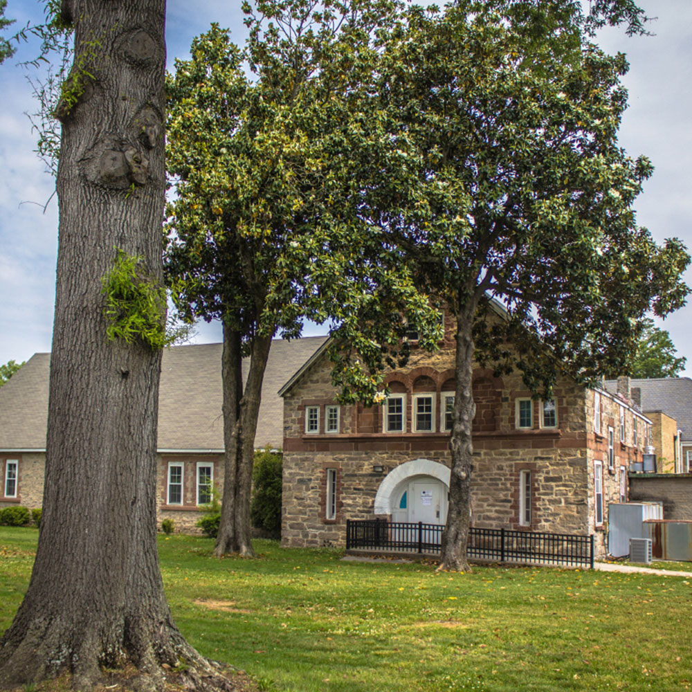 A historic brick and stone building surrounded by a few trees on St Augustine's campus in Wake County