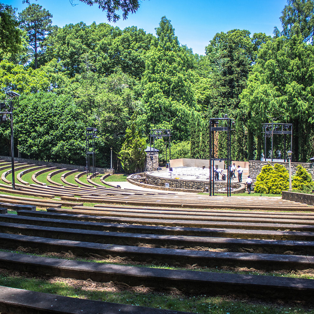 An ampitheater with rows of stone seats and production structures for light fixtures to illuminate the stage in Wake County