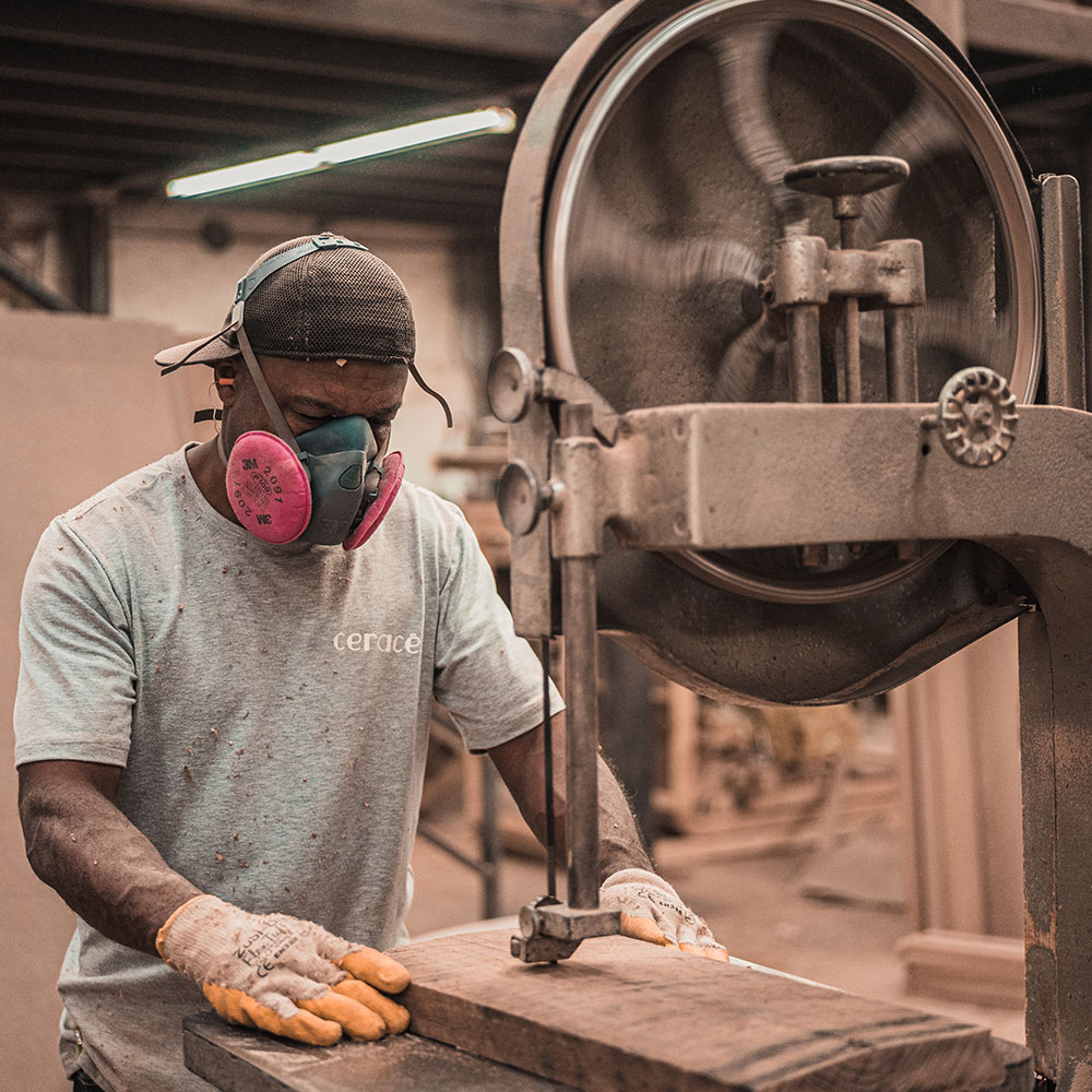 A man wearing a mask works with a large metal machine