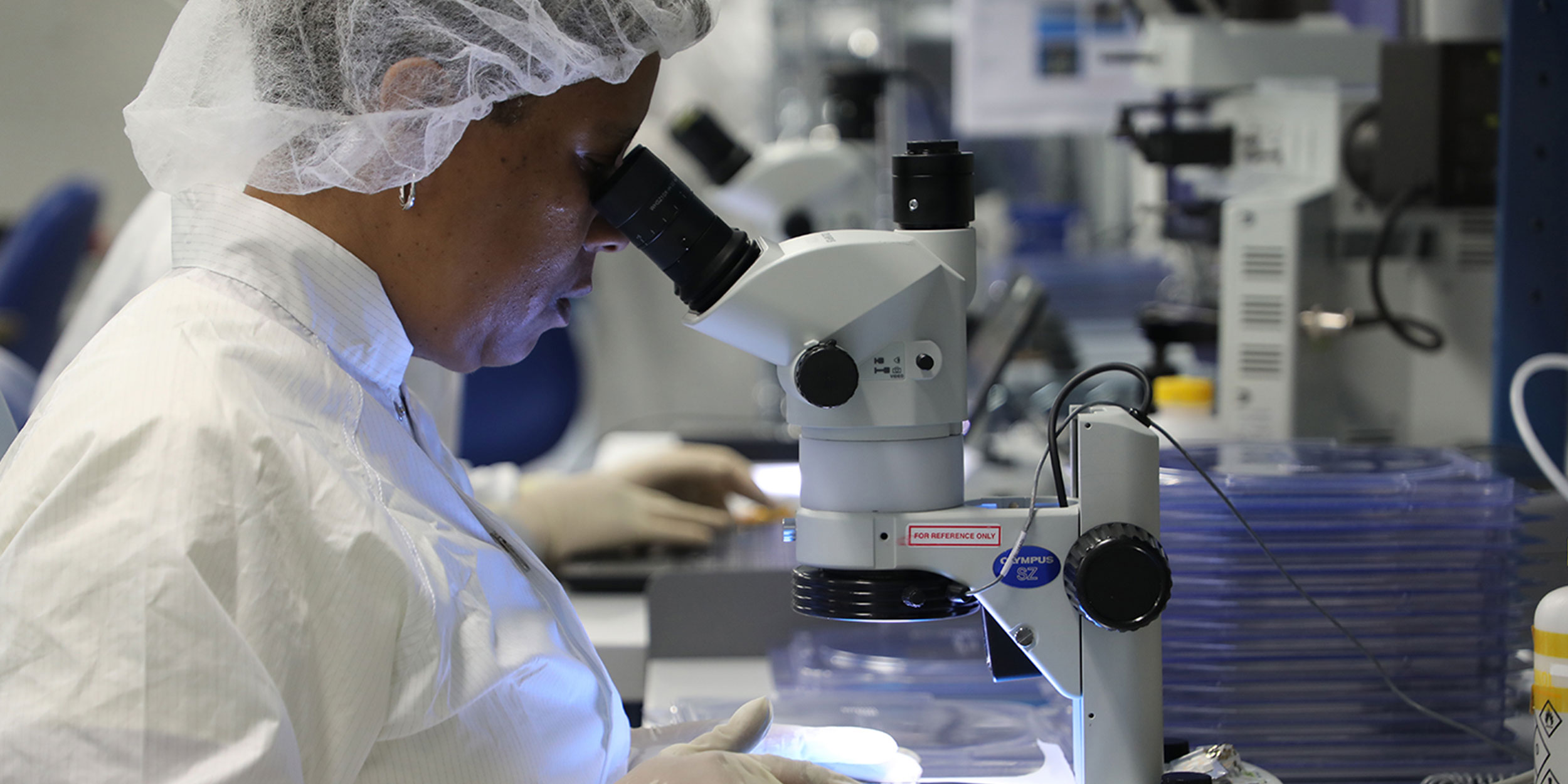 A woman looking into an advanced microscope in a research lab in Wake County