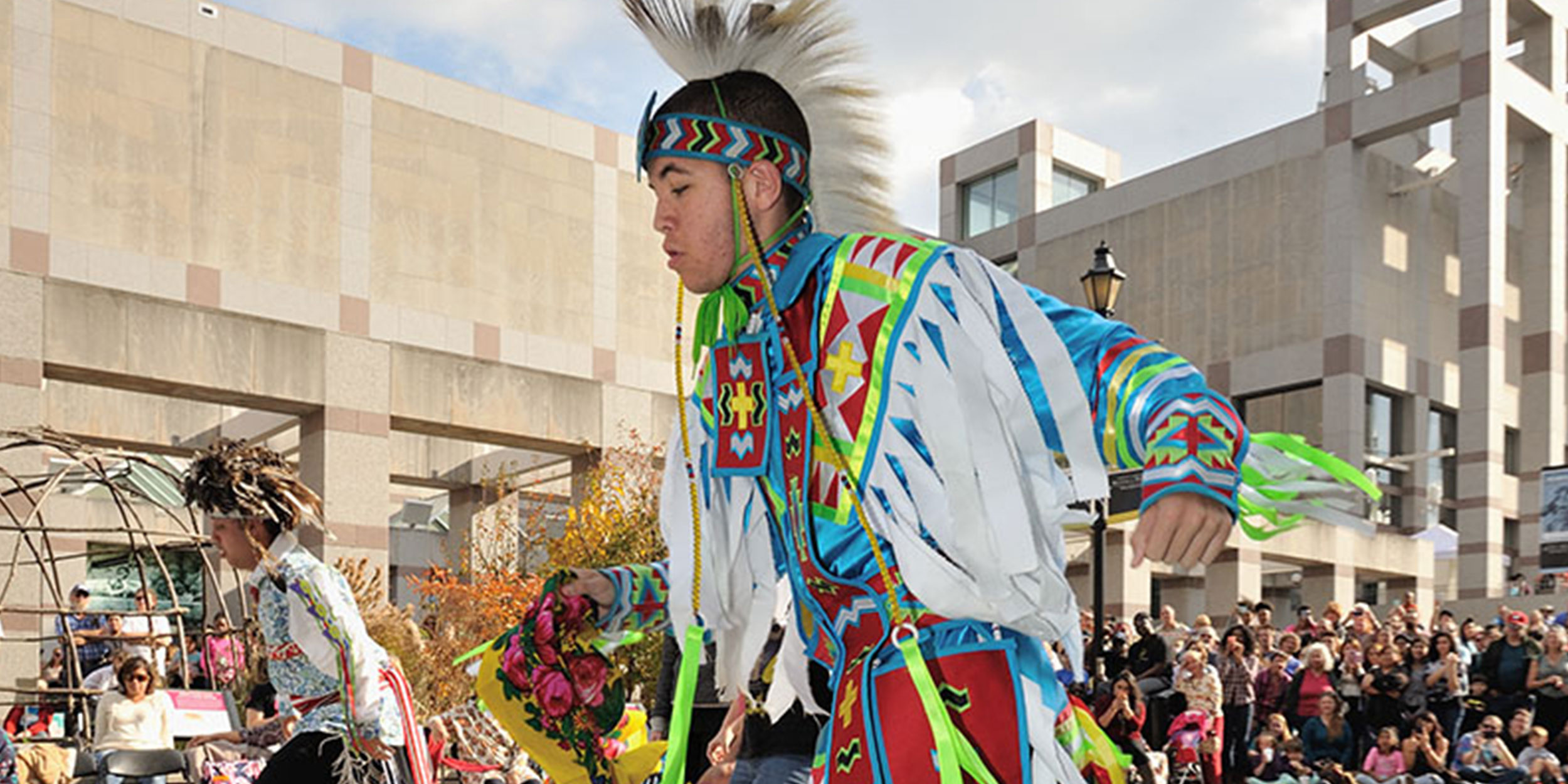 A young man dressed in blue and white traditional Native American clothing participates in a festival in Wake County