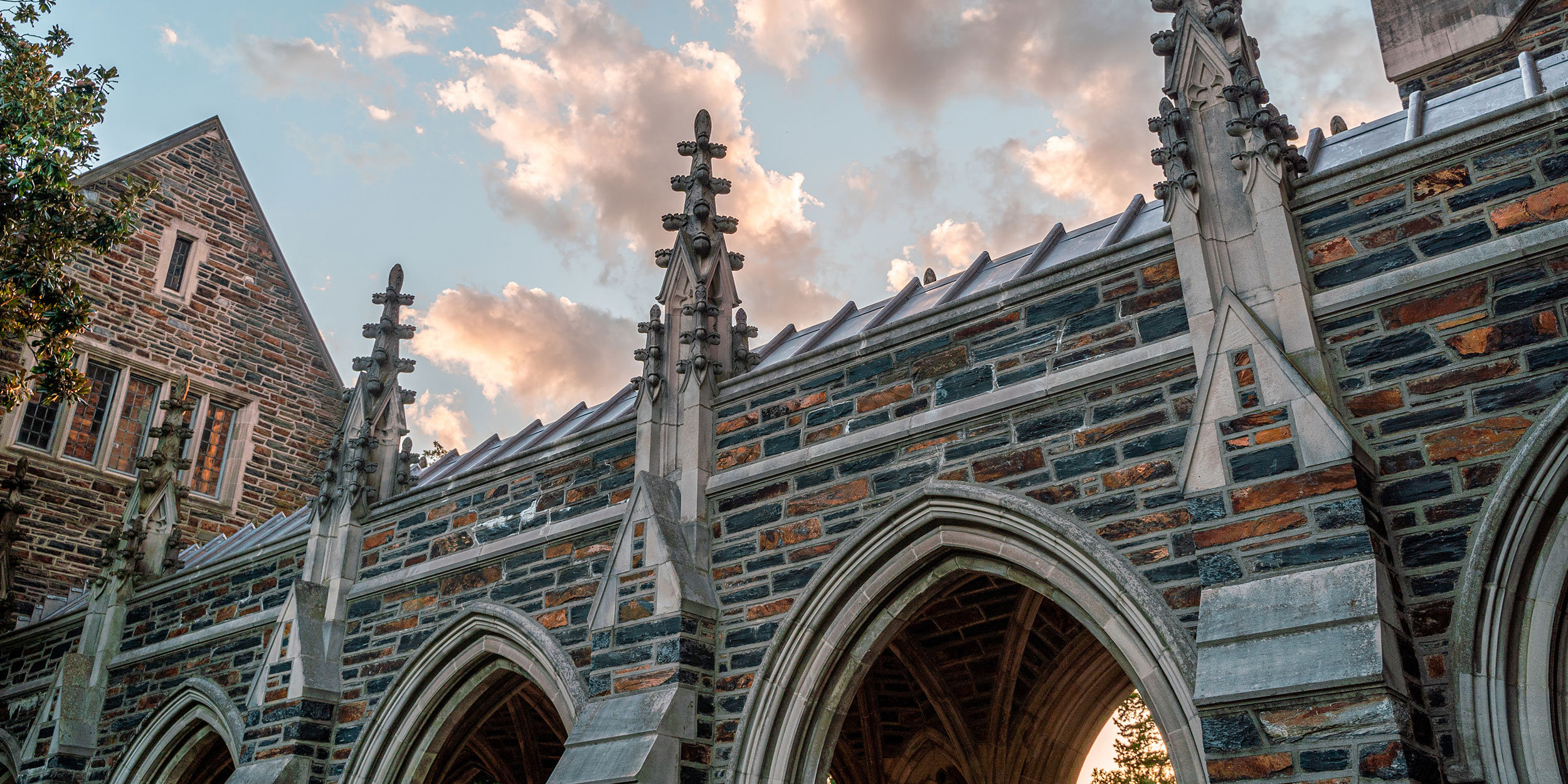 A ground advantage looking up at a gothic stone church spire with a blue, evening sky in the background in Wake County