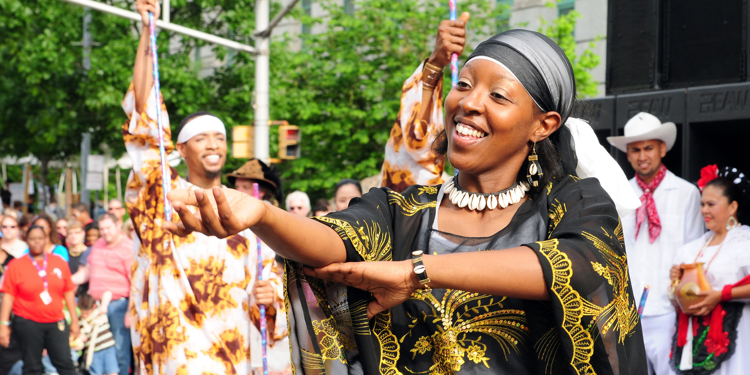 A woman smiles brightly as she dances in traditional African clothing at a festival in Wake County