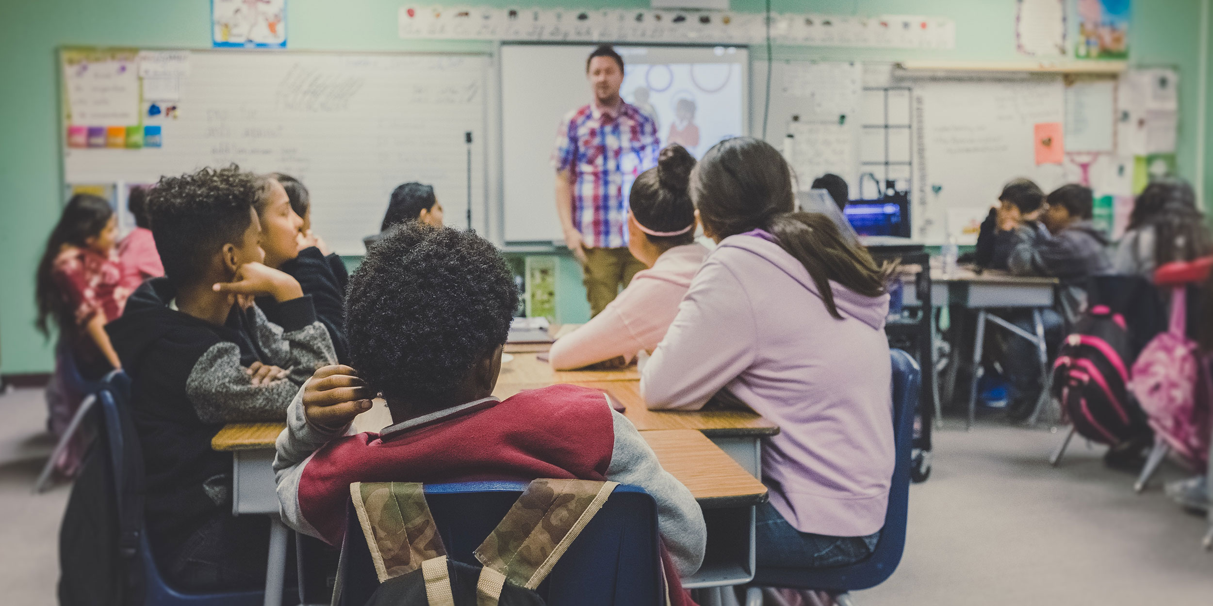 Students in a classroom listen to their teacher