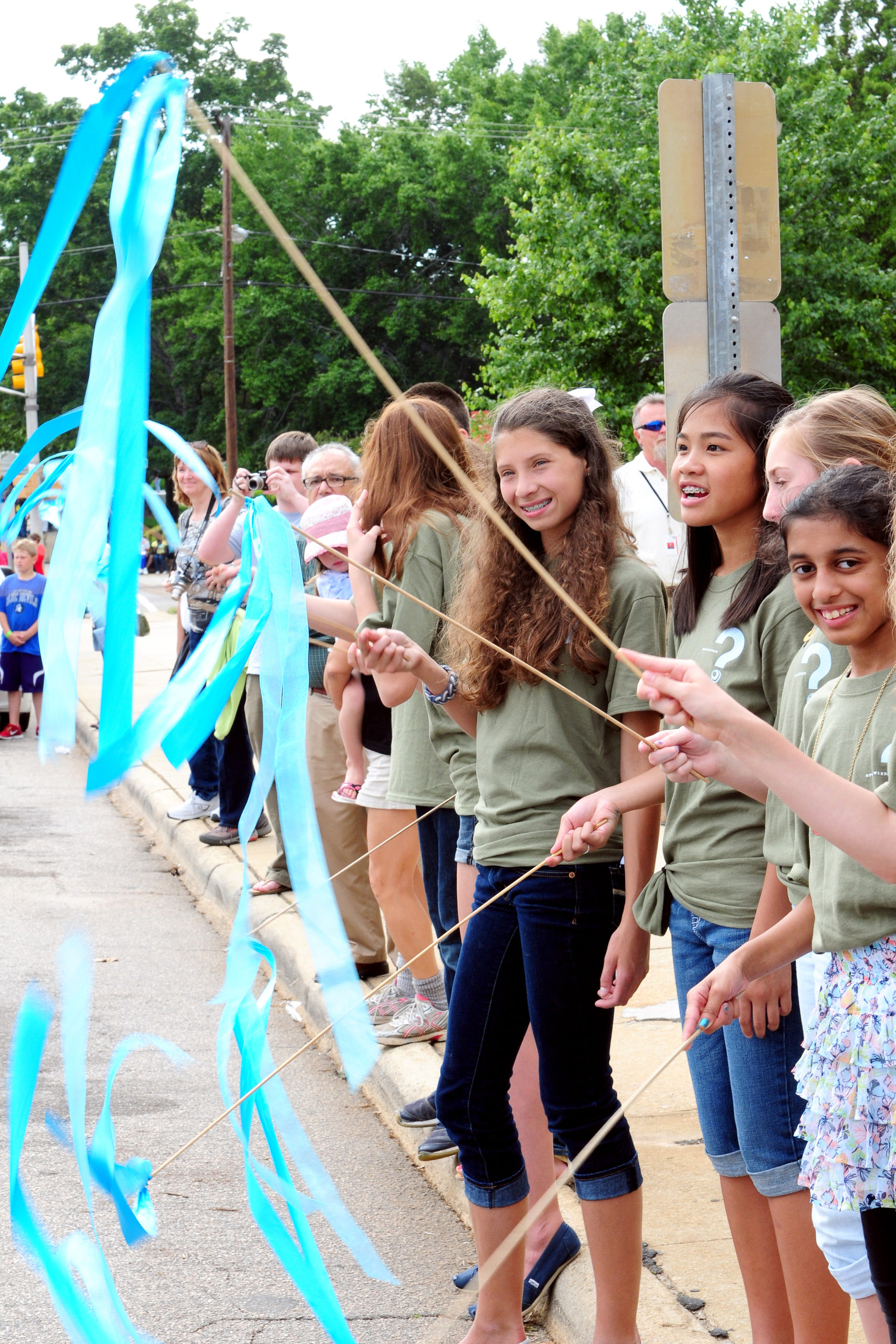 group of kids waving blue streamers on the sidewalk