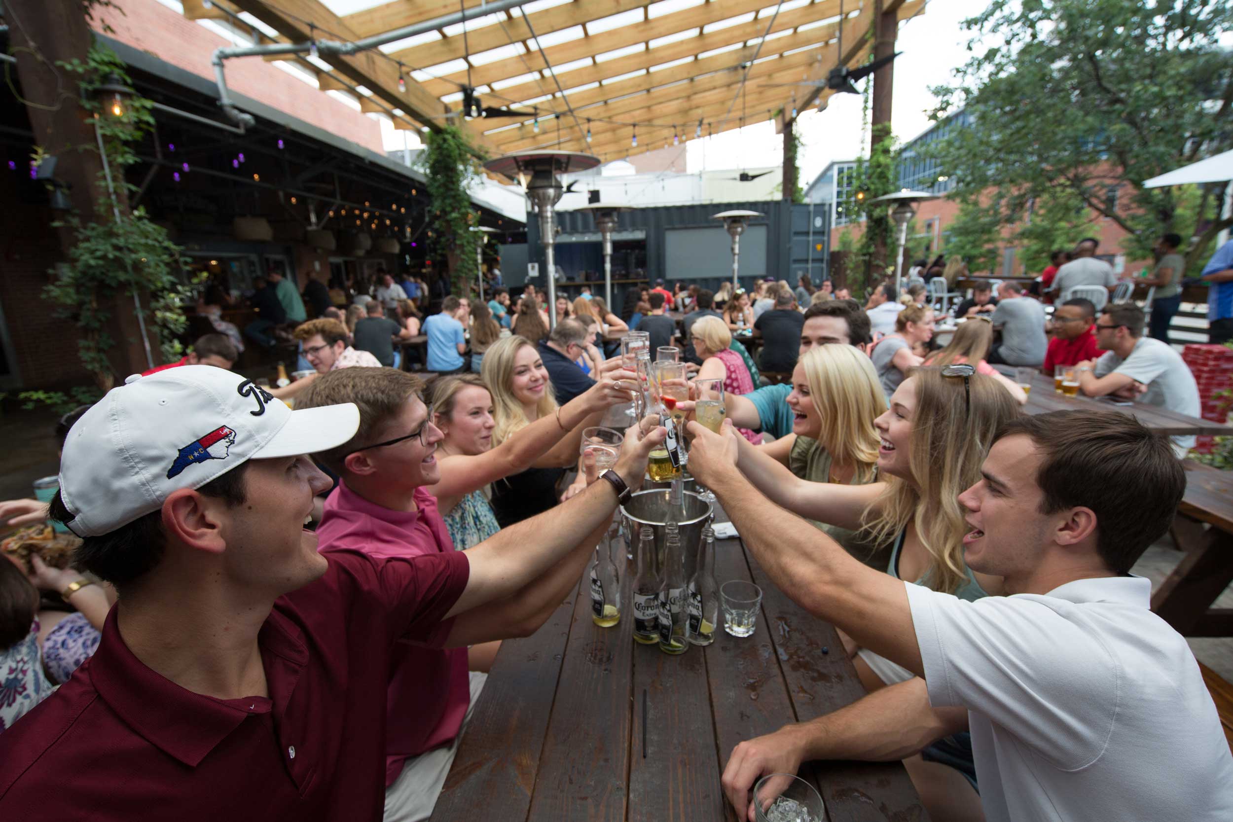 A group of friends raise their beer glasses at a table.