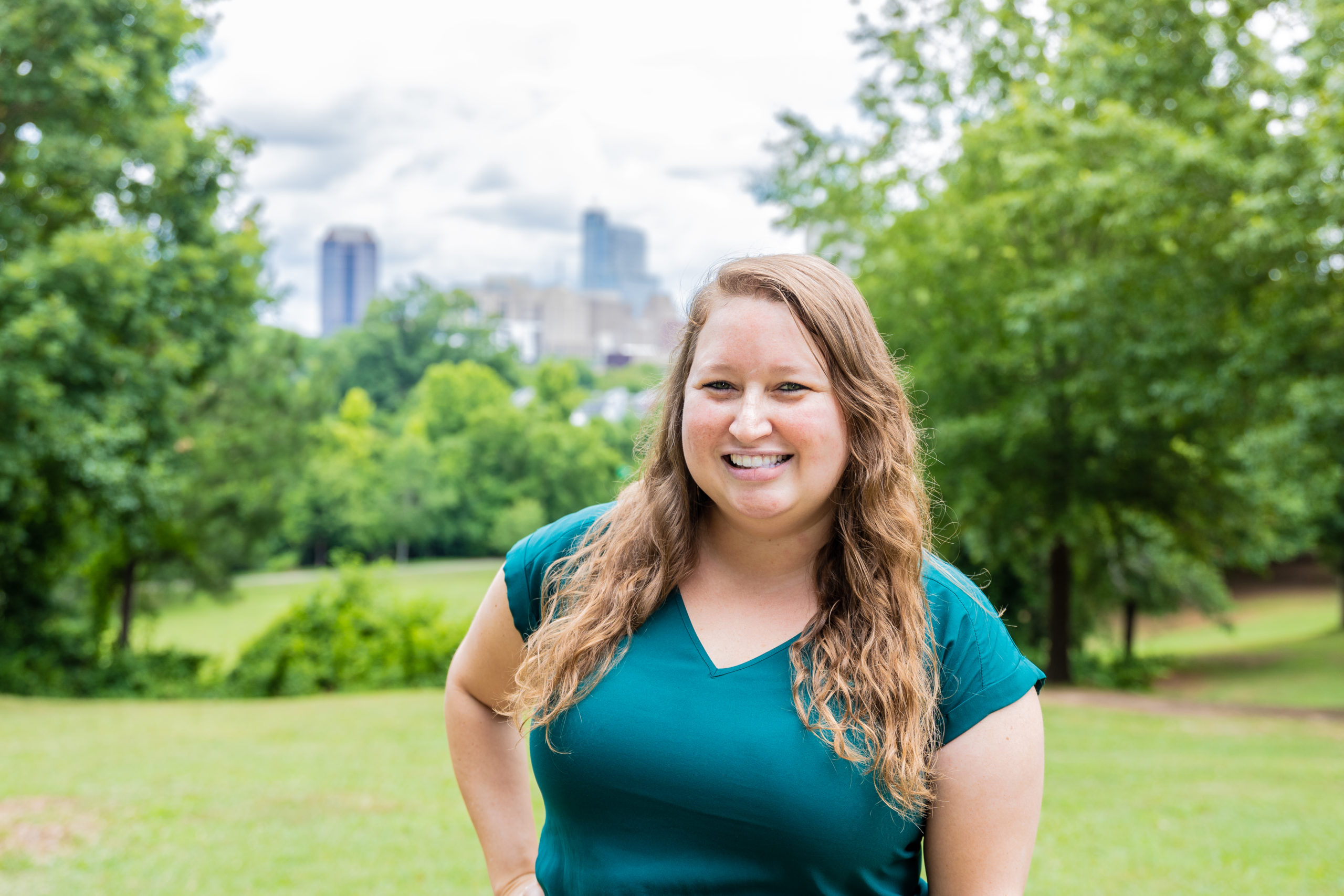Photo of Jessica Holt surrounded by greenery and buildings of Raleigh skyline
